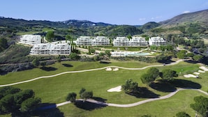 A golf course with a clubhouse and multiple white buildings with balconies. - Stunning Apartment Close to Golf, Mijas, Spain (Mijas)