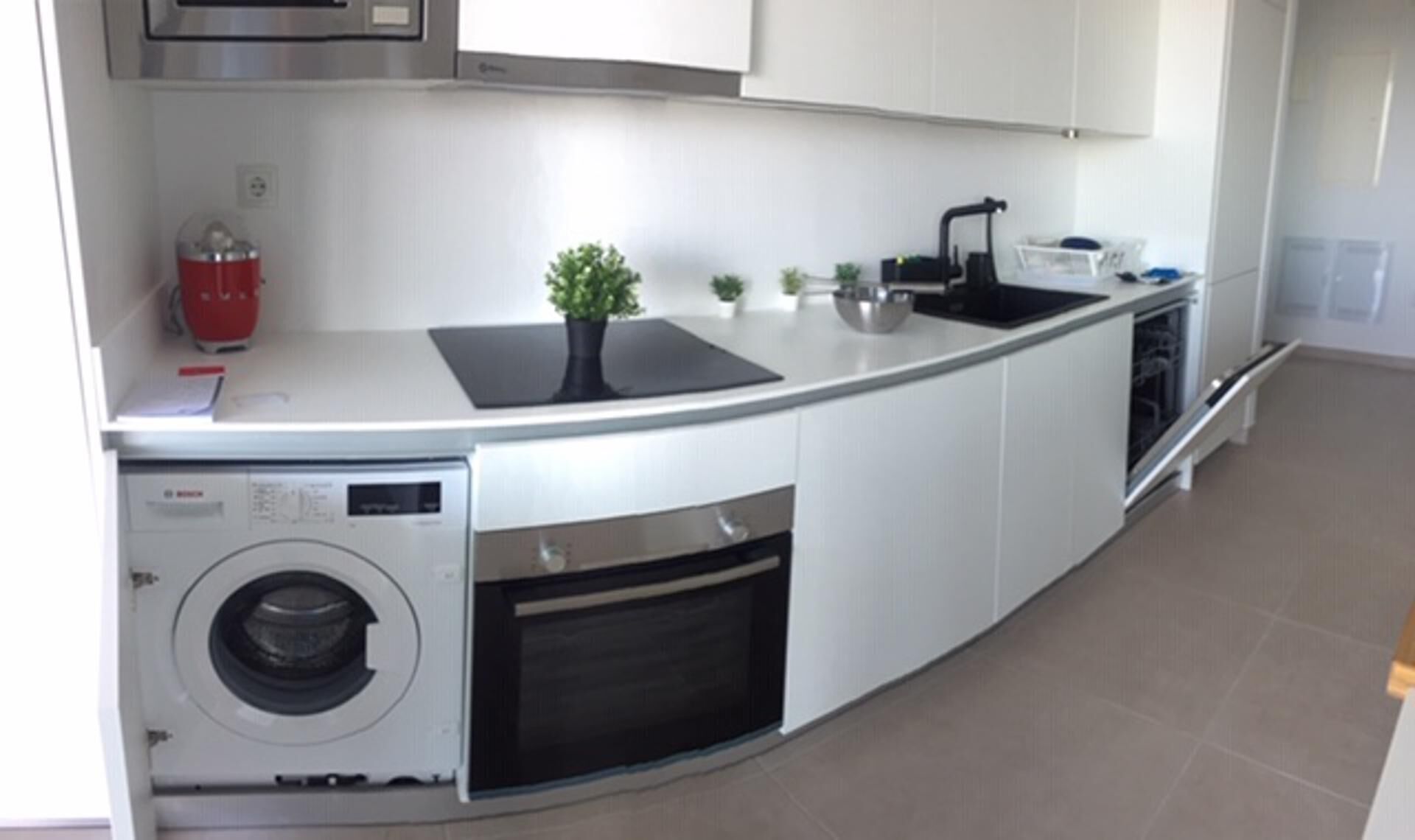 A compact kitchen with a built-in washing machine, oven, and microwave.