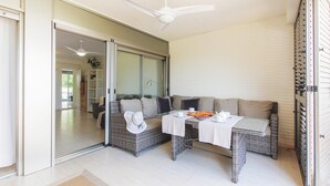 A modern living room with a glass door leading to a balcony, wicker furniture, and a table set with breakfast items. - Apartam Tierra del Mediterraneo Next to the Beach (Denia)