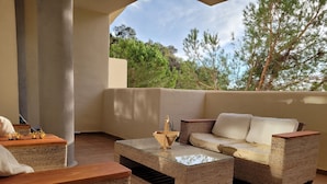 A balcony with wicker furniture, a glass table, and a view of trees. - Elviria 2-bed Apt, Sleeps 4, Pool, 20m to Beach (Marbella)