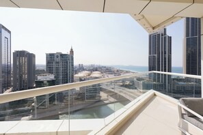 Un immeuble de grande hauteur doté d’un balcon en verre qui offre une vue sur le paysage urbain et une étendue d’eau.