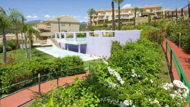 A resort with a pool, lush greenery, and multiple buildings in the background.