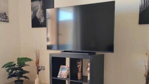Sala de estar con un mueble negro para entretenimiento que alberga un televisor de pantalla plana.