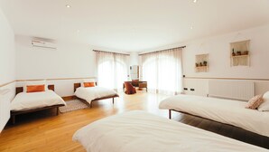 Une chambre d’hôtel avec deux lits simples, un plancher en bois, une commode, un miroir et un radiateur.