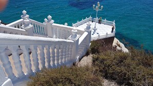Un balcon blanc aux balustrades décorées, donnant sur une mer d’un bleu limpide.