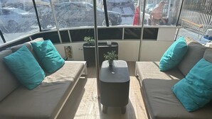 Een gezellige zithoek met twee banken en een kleine tafel, met turquoise kussens en een potplant.