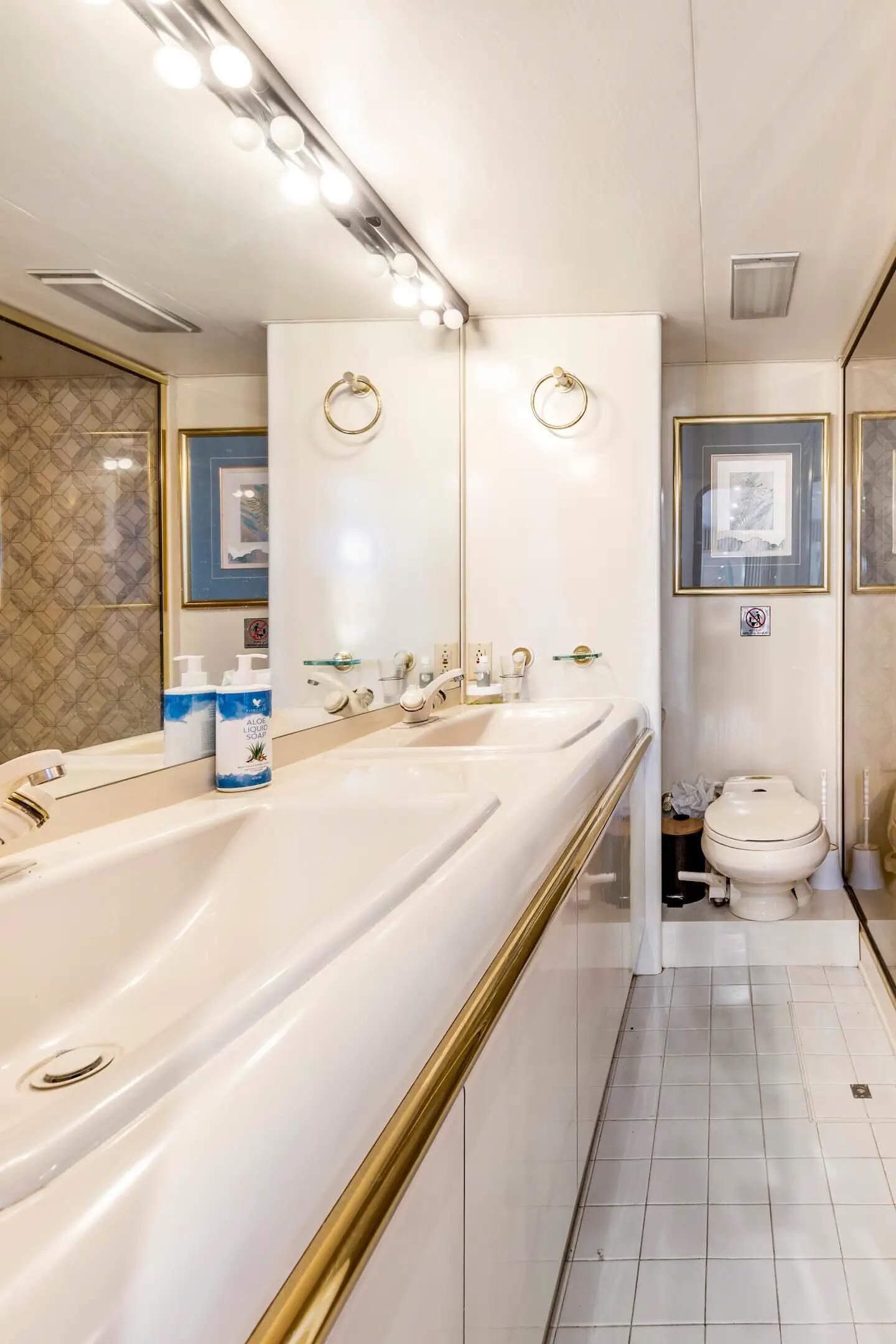 Une salle de bain moderne avec un long meuble-lavabo, un grand miroir et des toilettes.