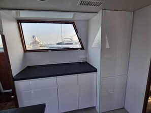 Une cuisine compacte avec une fenêtre donnant sur un port de plaisance.