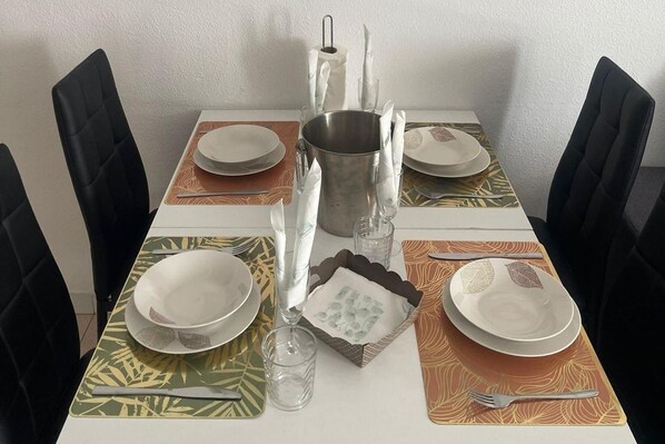 A dining table set with plates, cutlery, glasses, and a metal pitcher.