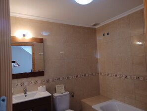 Et badeværelse med vask, toilet og badekar.