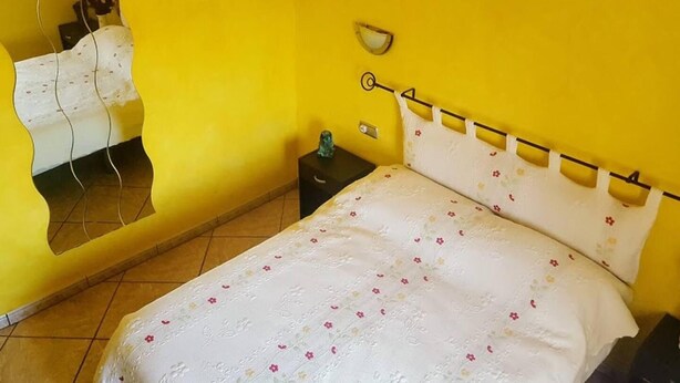 Ein Schlafzimmer mit Bett, Nachttisch, Spiegel und Wandlampe.