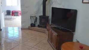 Ein Wohnzimmer mit Fernseher auf einer Holzkommode, einem Kamin und einem Essbereich mit Stühlen.