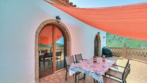 A patio with a table and chairs, a brick wall, and a view of a green landscape. - Casa Redonda a Tranquil Spacious Apartment (Còmpeta)