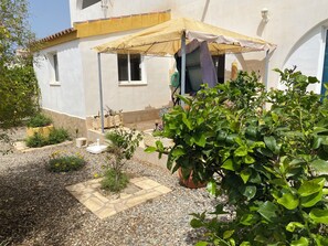 A courtyard with a pergola, potted plants, and a small garden area. - Luxury Beachfront Villa in La Perla (Arboleas)