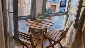 A corner room with a wooden table and two chairs, large windows with curtains, and a view of buildings outside. - Malaga Cityheart Stay Bright Modern City (Málaga)