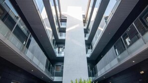 A modern building with a central atrium, multiple floors, and glass railings. - Malaga Cityheart Stay Bright Modern City (Málaga)