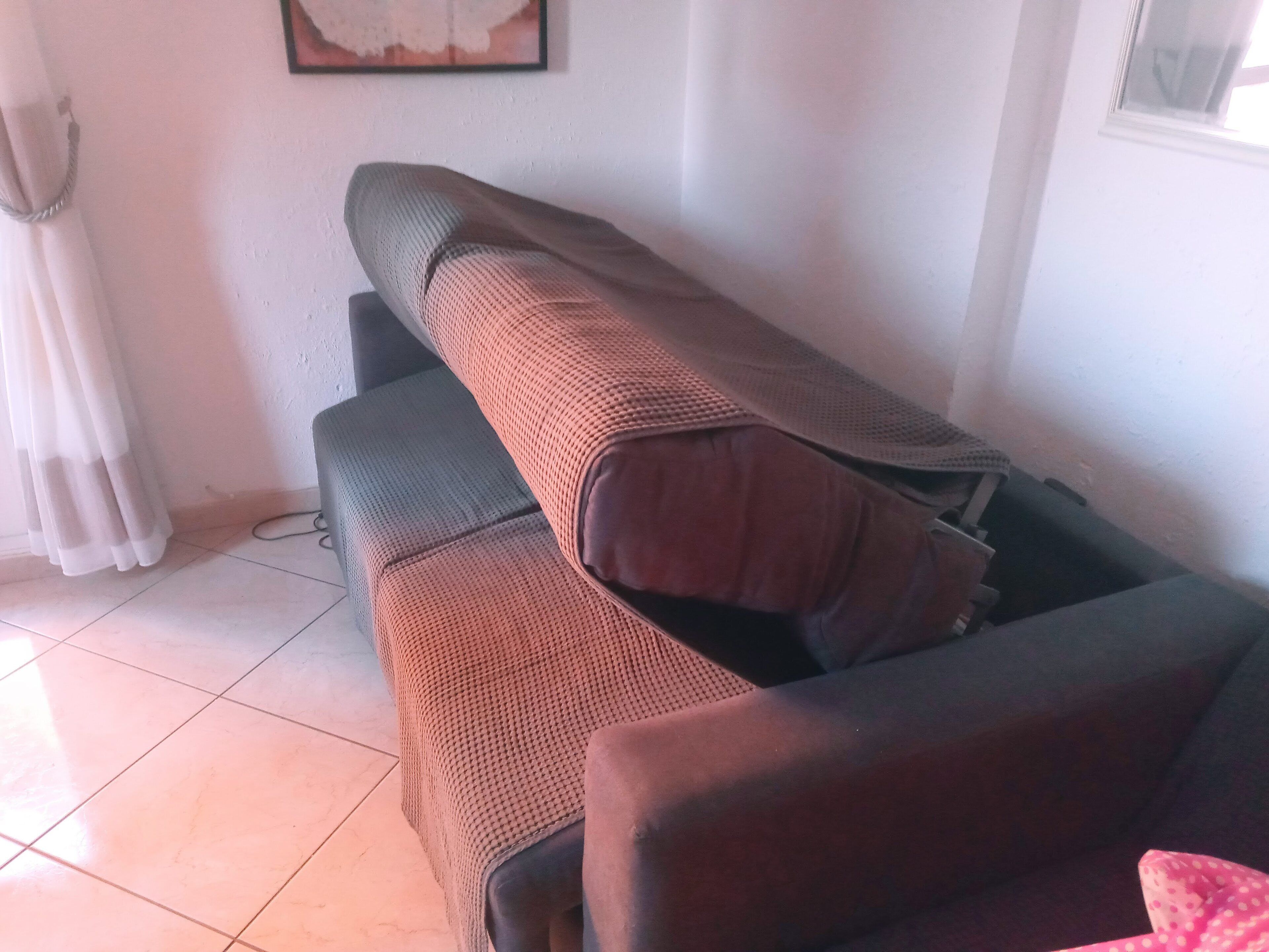 Ein Wohnzimmer mit einer Couch, einem kleinen Tisch und einem Fenster.