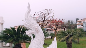 A white dragon sculpture in a garden with palm trees and a red flowering tree. - Minerva 1-bedroom, Close to the Beach, Park etc (Benalmádena)