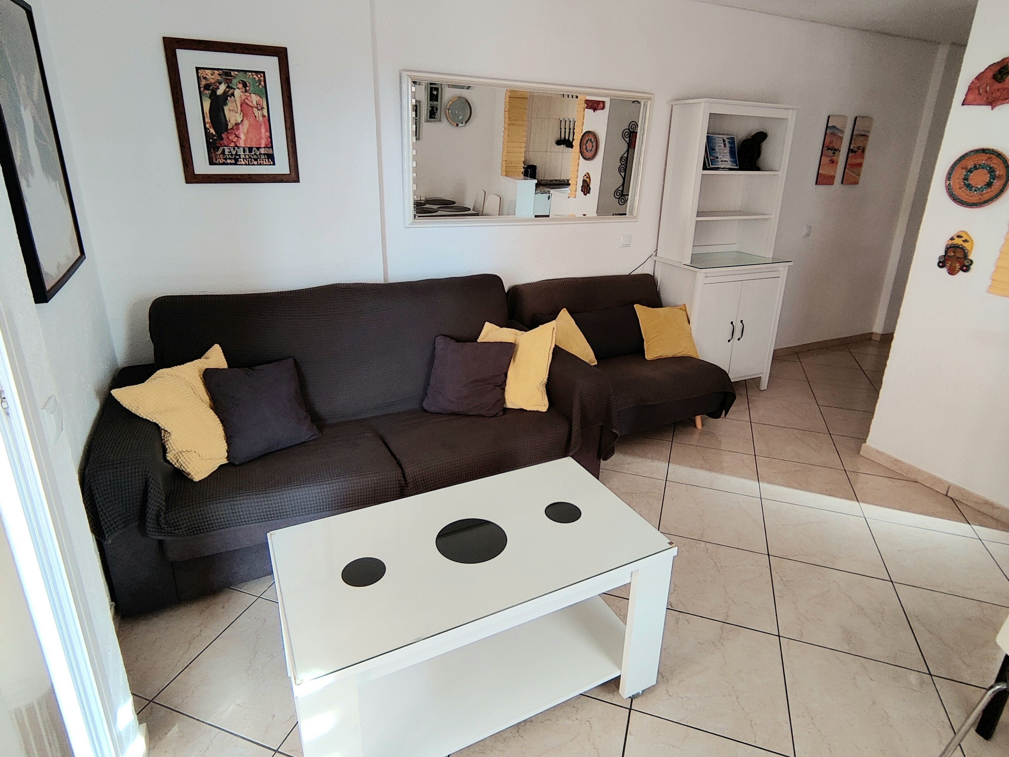 A living room with a brown sofa, a white coffee table, and a white cabinet.