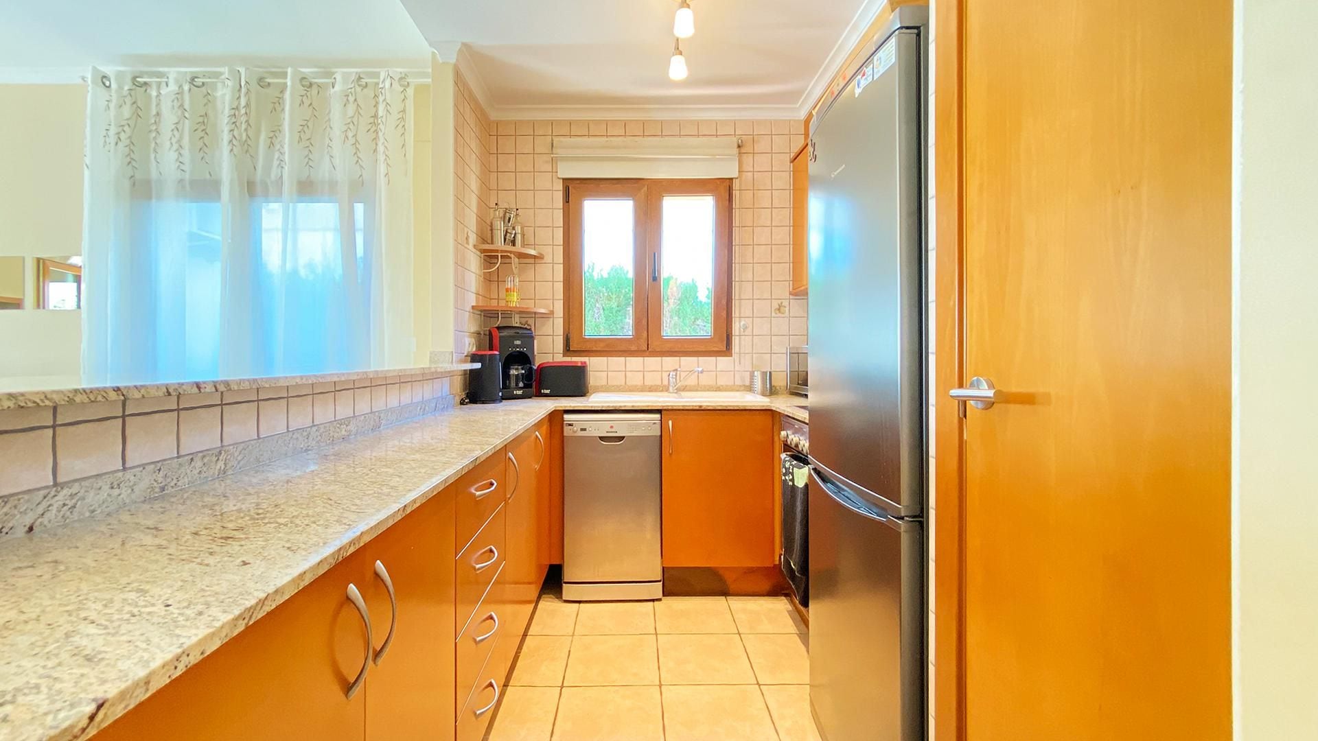 A compact kitchen with a dishwasher, a refrigerator, and a coffee maker.