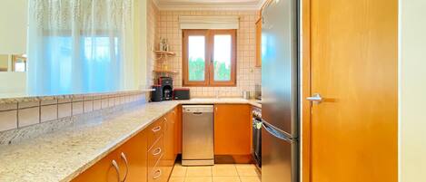 A compact kitchen with a dishwasher, a refrigerator, and a coffee maker.