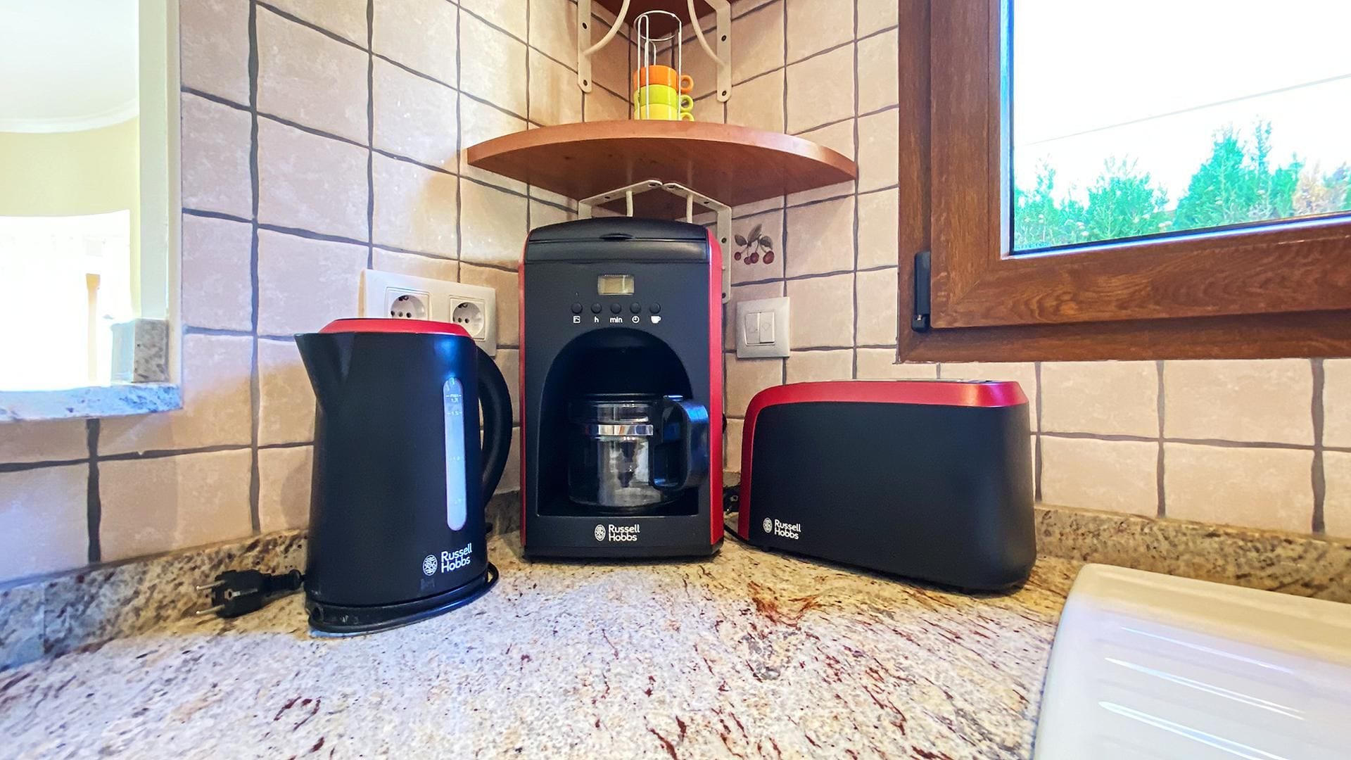 Una cucina con una macchina da caffè, un bollitore e un cestino.