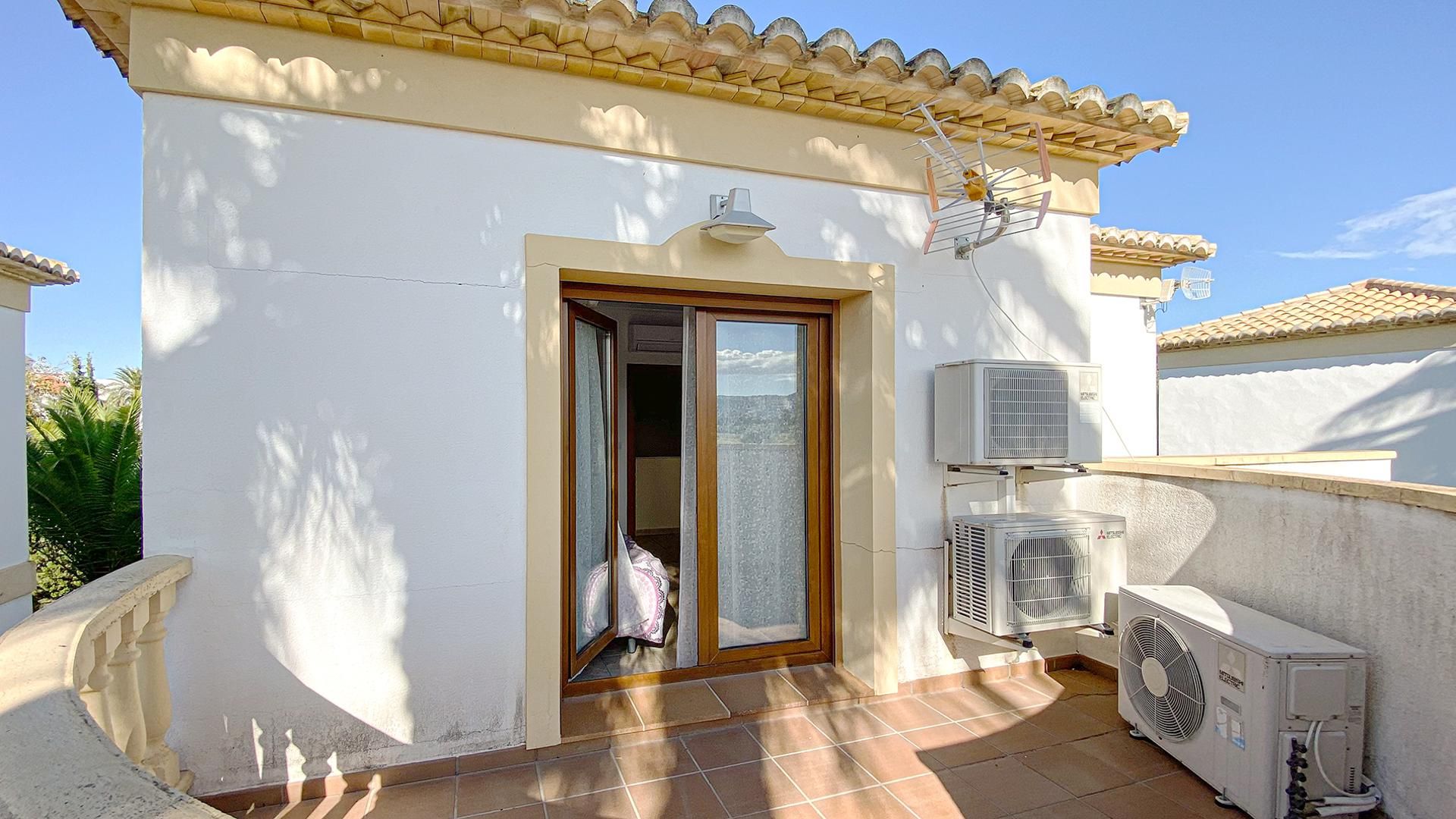A building with a tiled roof, a door with a glass panel, and two air conditioning units.