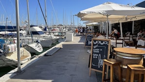 A marina with boats docked, outdoor seating, and a restaurant named 'yaya' with a chalkboard menu. - Newly Refurbished Luxury 3 Bed Duplex Apartment (Fuengirola)