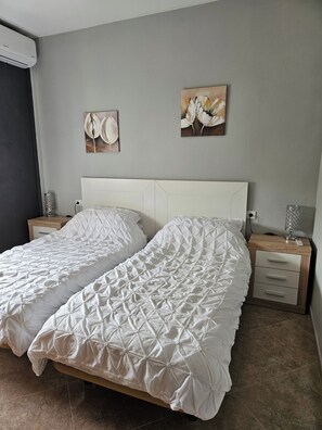 Un letto matrimoniale con una coperta a motivi geometrici, un comodino con una lampada e due opere d'arte appese al muro.