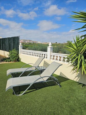 Un patio con due poltrone da relax e un recinto decorativo bianco.