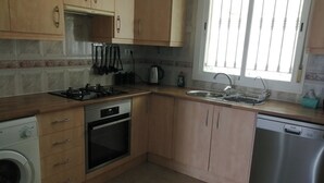 A kitchen with wooden cabinets, a stove, oven, washing machine, sink, and dishwasher. - Villa - Sleeps 4 - Pool - Patio - Parking (Arboleas)