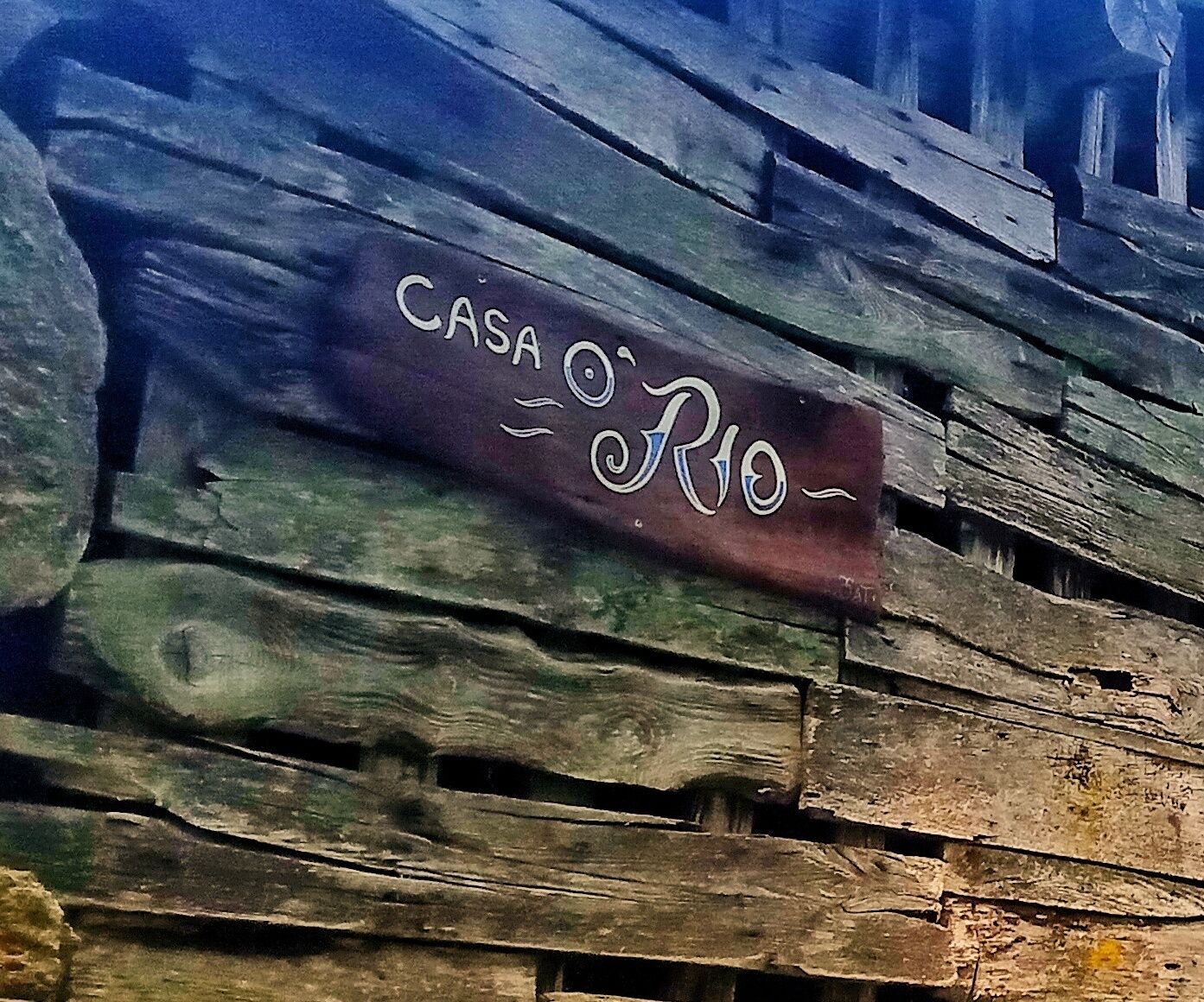 A rustic wooden wall with the text "CASA O'RIO" painted on it.