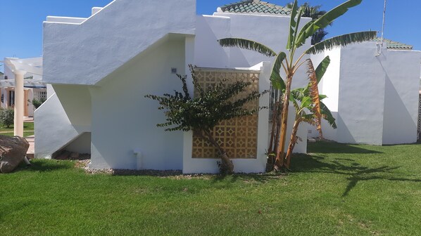 A modern building with white walls and a geometric design, featuring a small garden with a palm tree and a patterned wall. - Cozy Coastal Retreat in San Juan de Los Terreros (Pulpi)