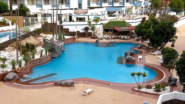 A swimming pool with lounge chairs and a bar in the background. - Cousy Holiday Apartment in Sunny Golf del Sur (San Miguel de Abona)