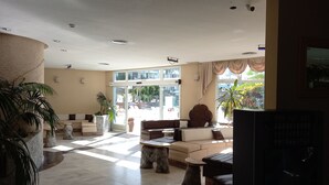 A spacious lobby with a large seating area, a reception desk, and a view of the outdoor area through large glass doors. - Cousy Holiday Apartment in Sunny Golf del Sur (San Miguel de Abona)