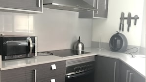 A modern kitchen with grey cabinets, a stainless steel range hood, a built-in oven, a microwave, and a kettle. - Stunning 2-bed Apartment in Pego (Pego)