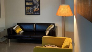 A living room with a black sofa, a yellow armchair, a floor lamp, and a framed picture on the wall. - Stunning 2-bed Apartment in Pego (Pego)