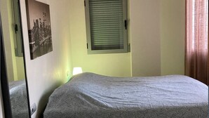 A bedroom with a bed, a window with blinds, a wall-mounted picture, and a mirror. - Stunning 2-bed Apartment in Pego (Pego)