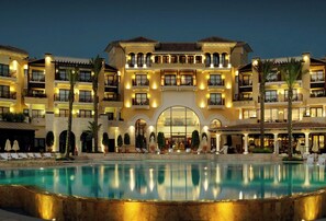 Un hôtel à plusieurs étages doté d’une piscine centrale dans un patio, de balcons et d’une ambiance chaleureuse et accueillante.