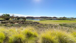A golf course with a lake, buildings in the background, and a clear blue sky. - Apt Sleeps 4 With Pool Access (Torre-Pacheco)