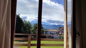 A balcony with a wooden railing, a view of green grass, and buildings in the background. - Charming 6-bed Chalet in Llanes (Llanes)