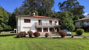 A two-story house with a balcony, a car parked in front, and a well-maintained lawn. - Charming 6-bed Chalet in Llanes (Llanes)