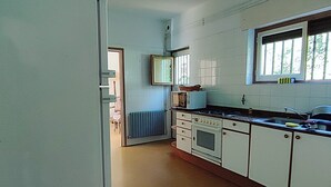 A kitchen with white cabinets, a stove, and a window. - Charming 6-bed Chalet in Llanes (Llanes)