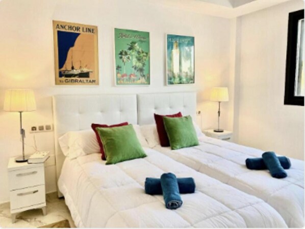 A hotel room with two beds, white bedding, green and red pillows, and artwork on the wall. - Premium Luxury-casares Del Mar-seaside Apartment (Casares)