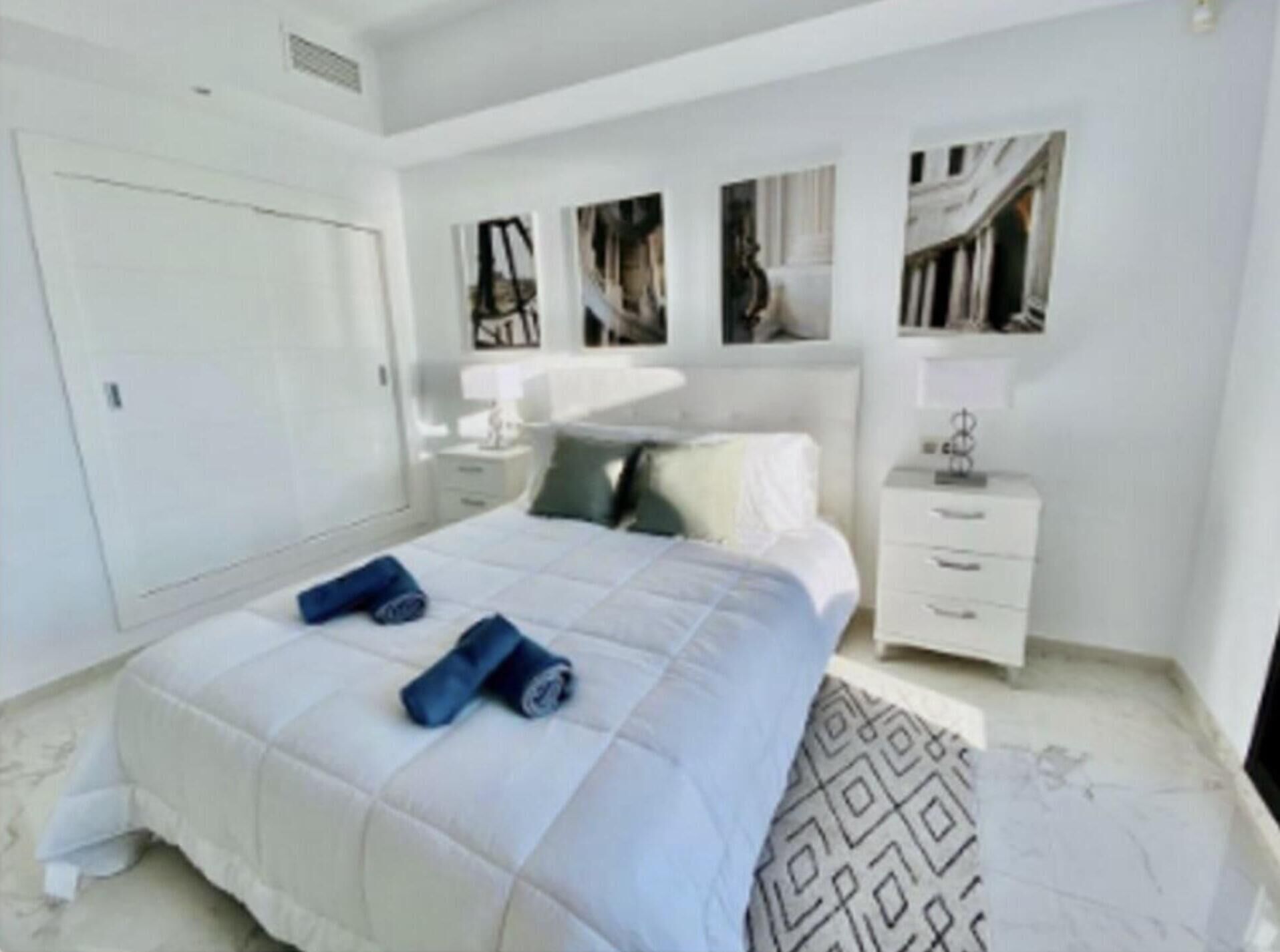 A bedroom with a bed, a nightstand, a dresser, and a mirror.
