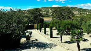 A pathway leading through a landscaped area with trees and a view of a hilly landscape under a clear blue sky. - Stunning 3 Bedroom Rural Apartment Near Pinoso (Pinoso)