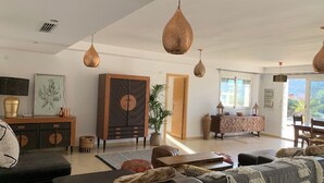 A spacious living room with a large sofa, a coffee table, and hanging pendant lights. There is a wooden cabinet and a potted plant in the room. - Stunning 3 Bedroom Rural Apartment Near Pinoso (Pinoso)