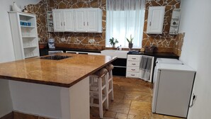 A kitchen with a granite countertop, white cabinets, and a stone backsplash. - Andalusian Pool Parties, Music & Magic (Coin)