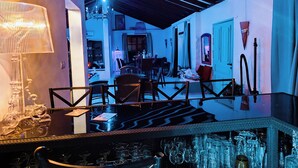 A bar area with a glass counter, chairs, and a variety of glassware. - Andalusian Pool Parties, Music & Magic (Coin)