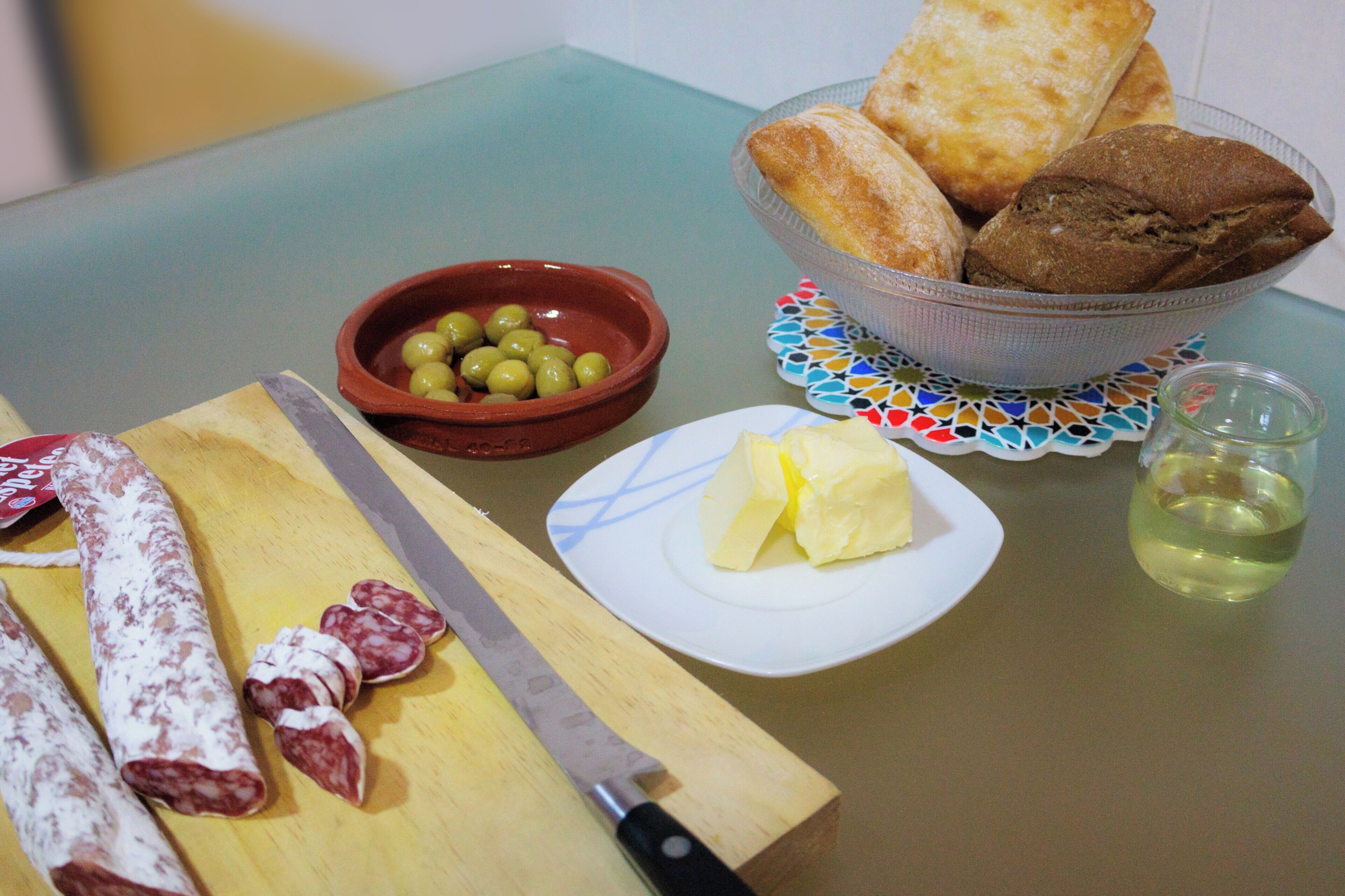 A table with a variety of food items including bread, olives, cheese, and cured meats.